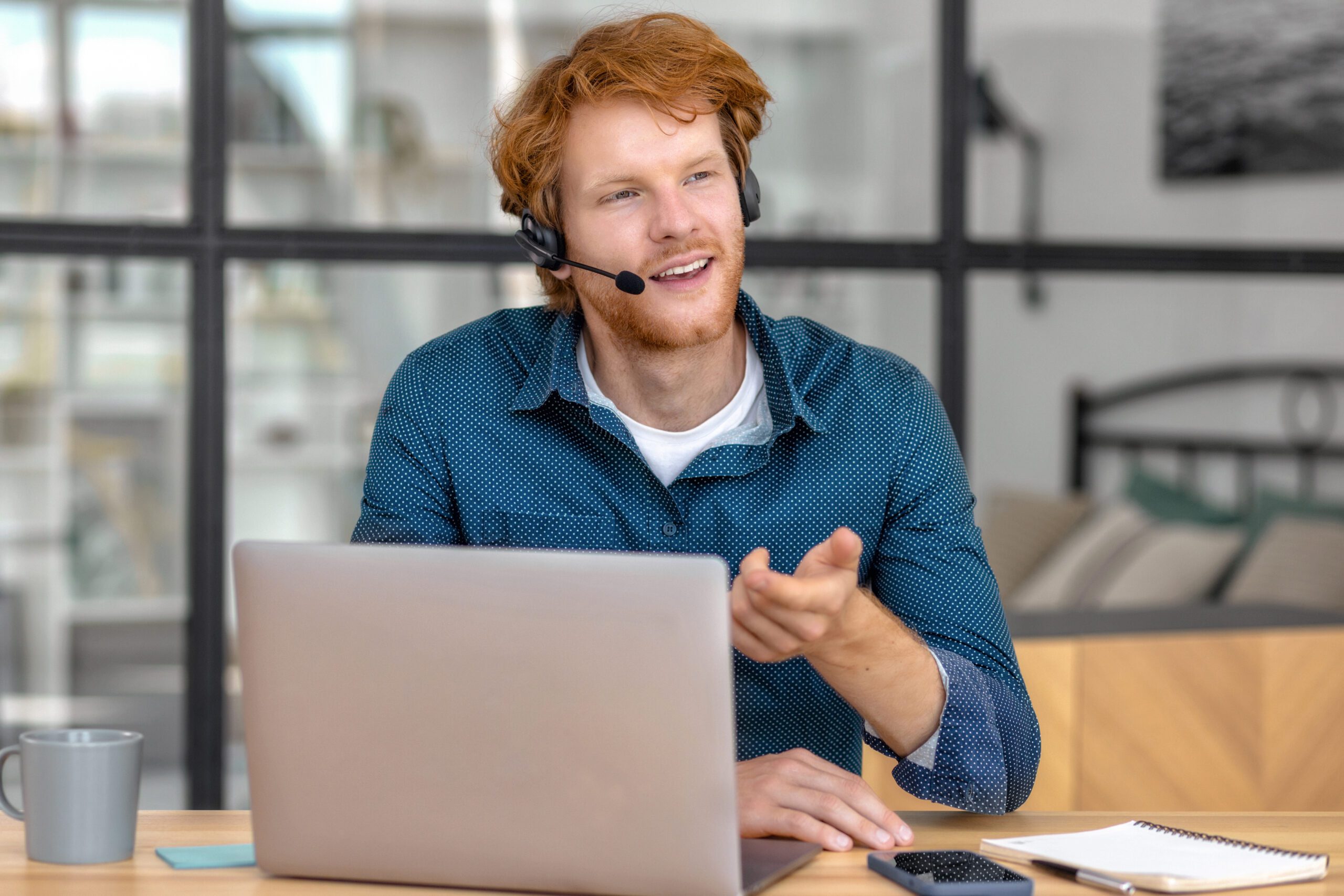 Man with headset working on laptop.