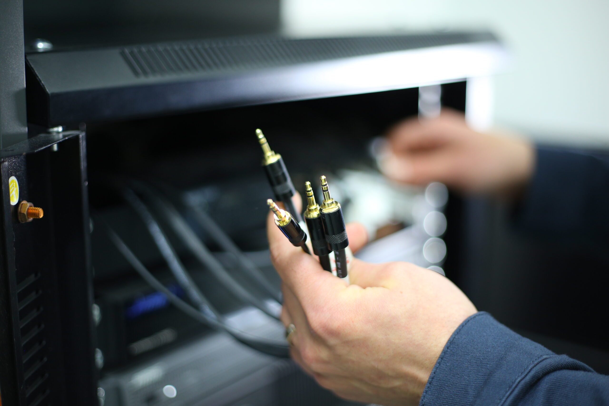 Hands holding audio cables near equipment.