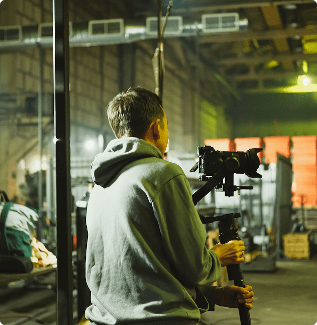 Person filming in industrial setting with camera.