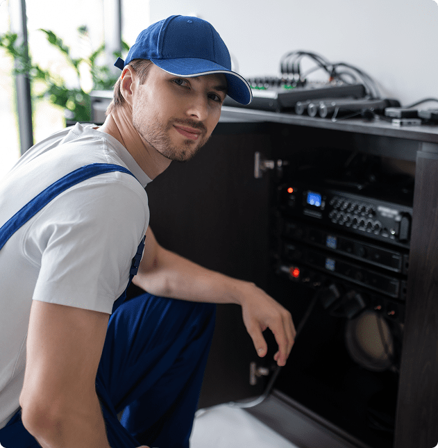 Technician adjusting audio equipment in cabinet.